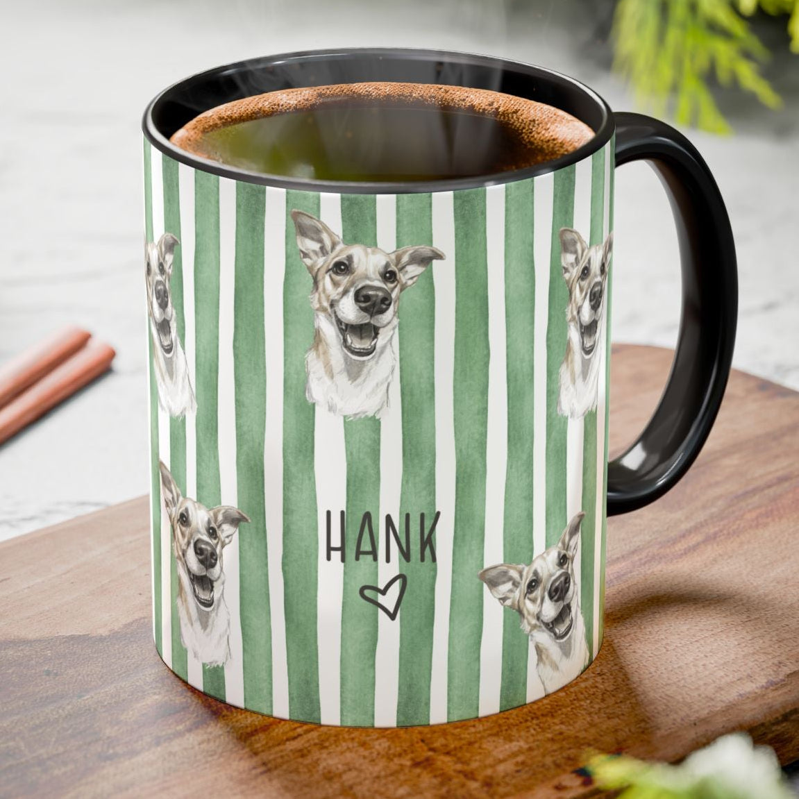 Green striped mug with dog pattern and 'Hank' text on a wooden board with pinecones and cinnamon sticks.